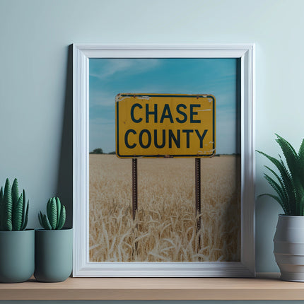 Yellow Chase County sign in a framed picture above wheat fields.