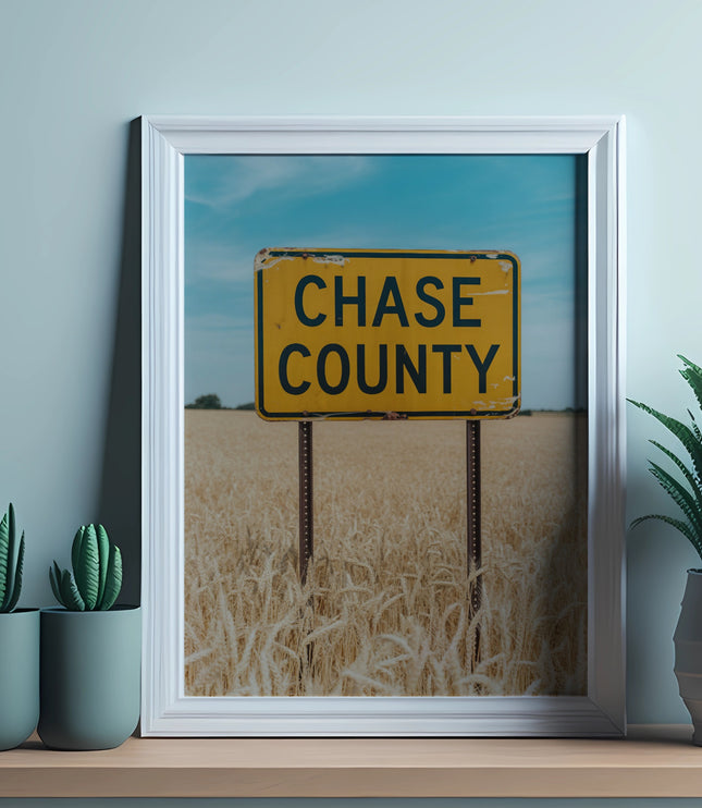 Yellow Chase County sign in a framed picture above wheat fields.
