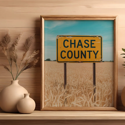 Framed sign for Chase County above a field of dry wheat.