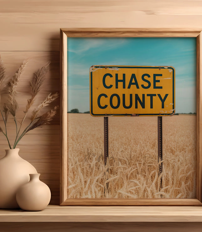 Framed sign for Chase County above a field of dry wheat.
